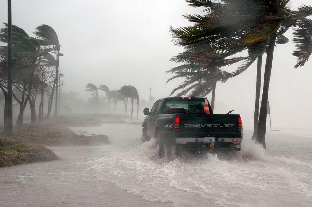 Climate change travel pickup truck in flood and storm winds